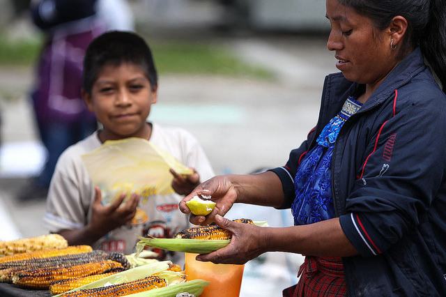 Una mujer prepara elote asado en México