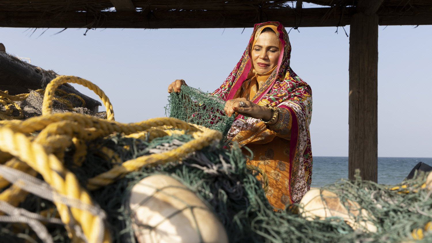 Oman - Omani coastal woman repairing a fishing net