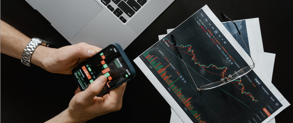 hands holding phone and paper with statistics and glasses